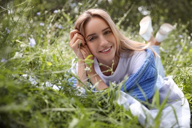 Portrait of beautiful young woman on green grass in park