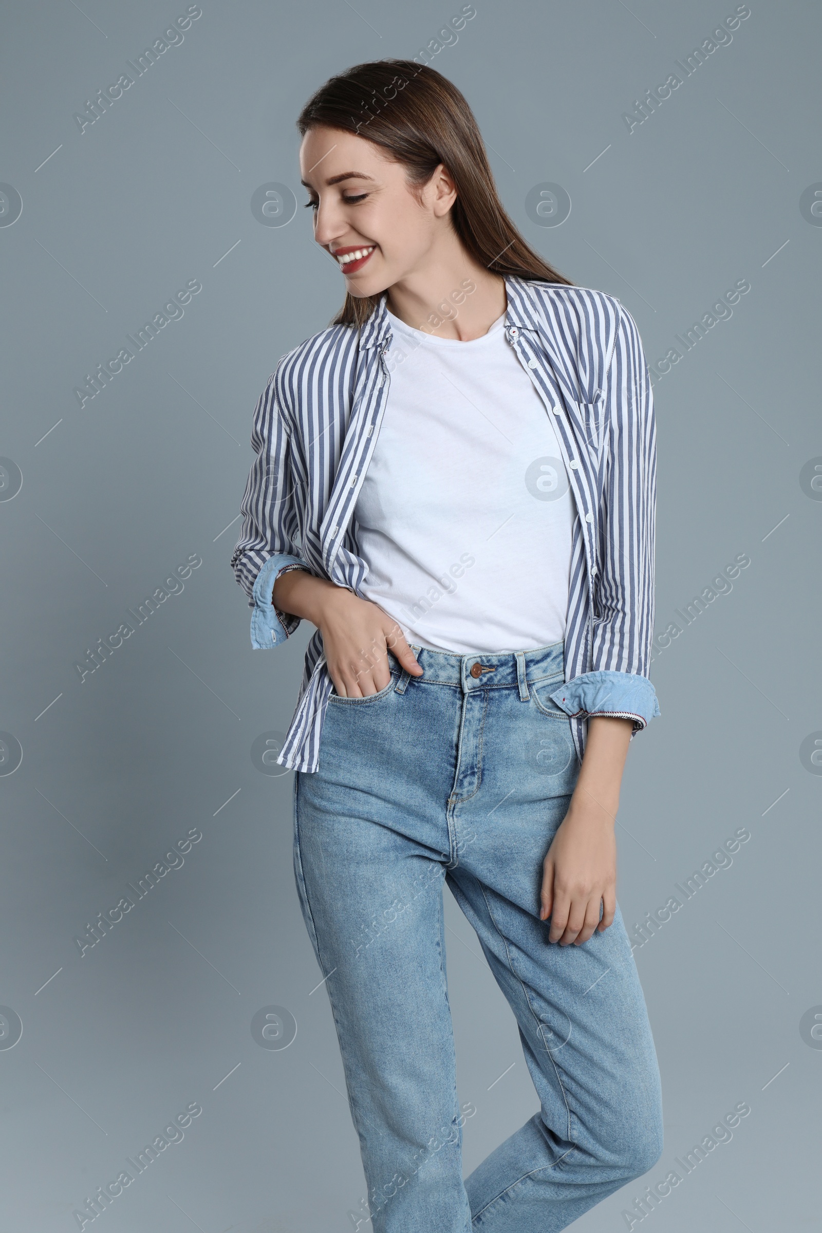 Photo of Young woman in stylish jeans on grey background