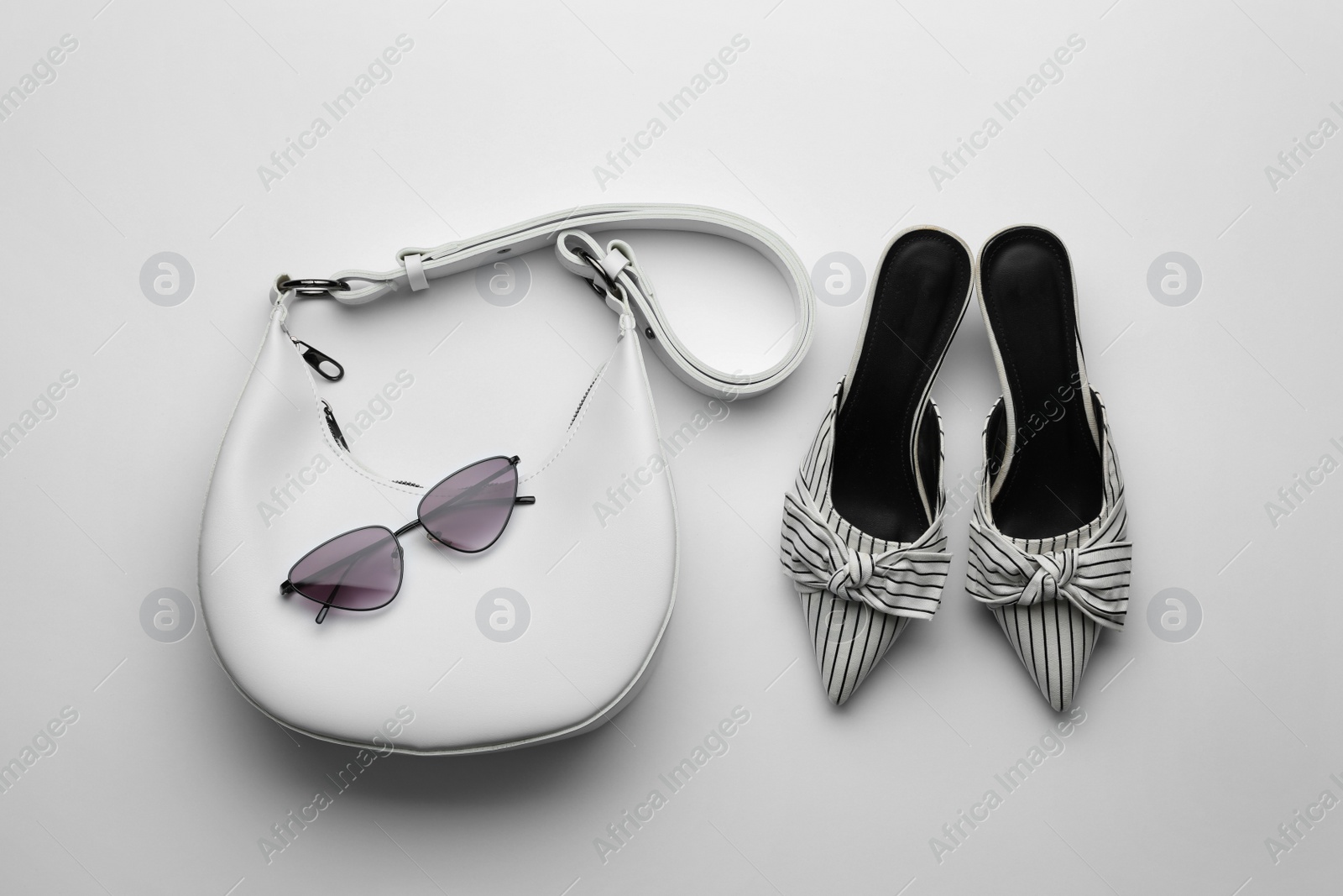 Photo of Stylish woman's bag, sunglasses and shoes on light background, flat lay