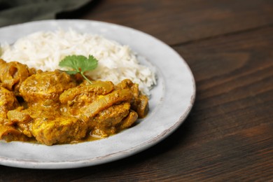 Photo of Delicious chicken curry with rice on wooden table, closeup