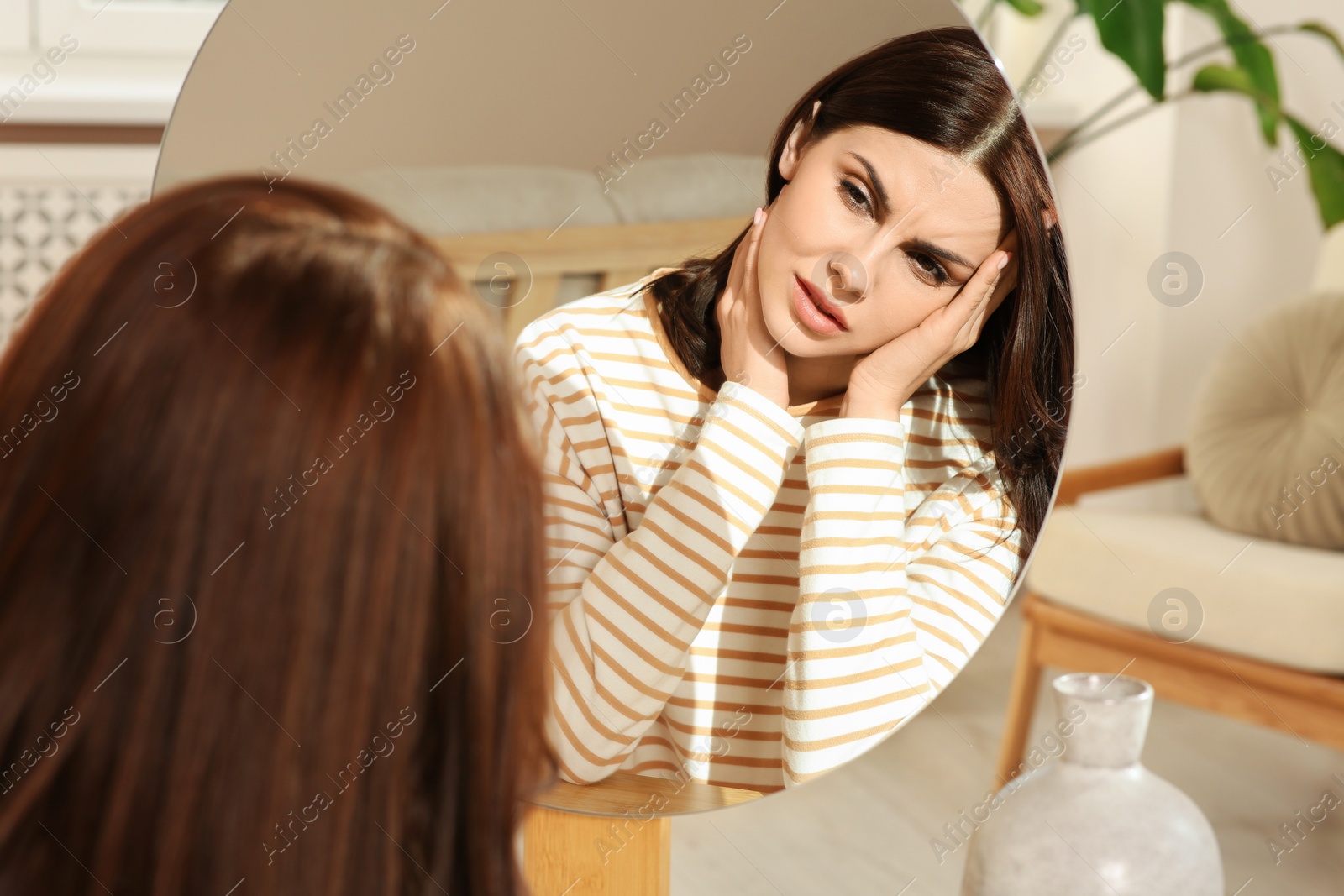 Photo of Unhappy woman looking in mirror indoors. Hormonal disorders