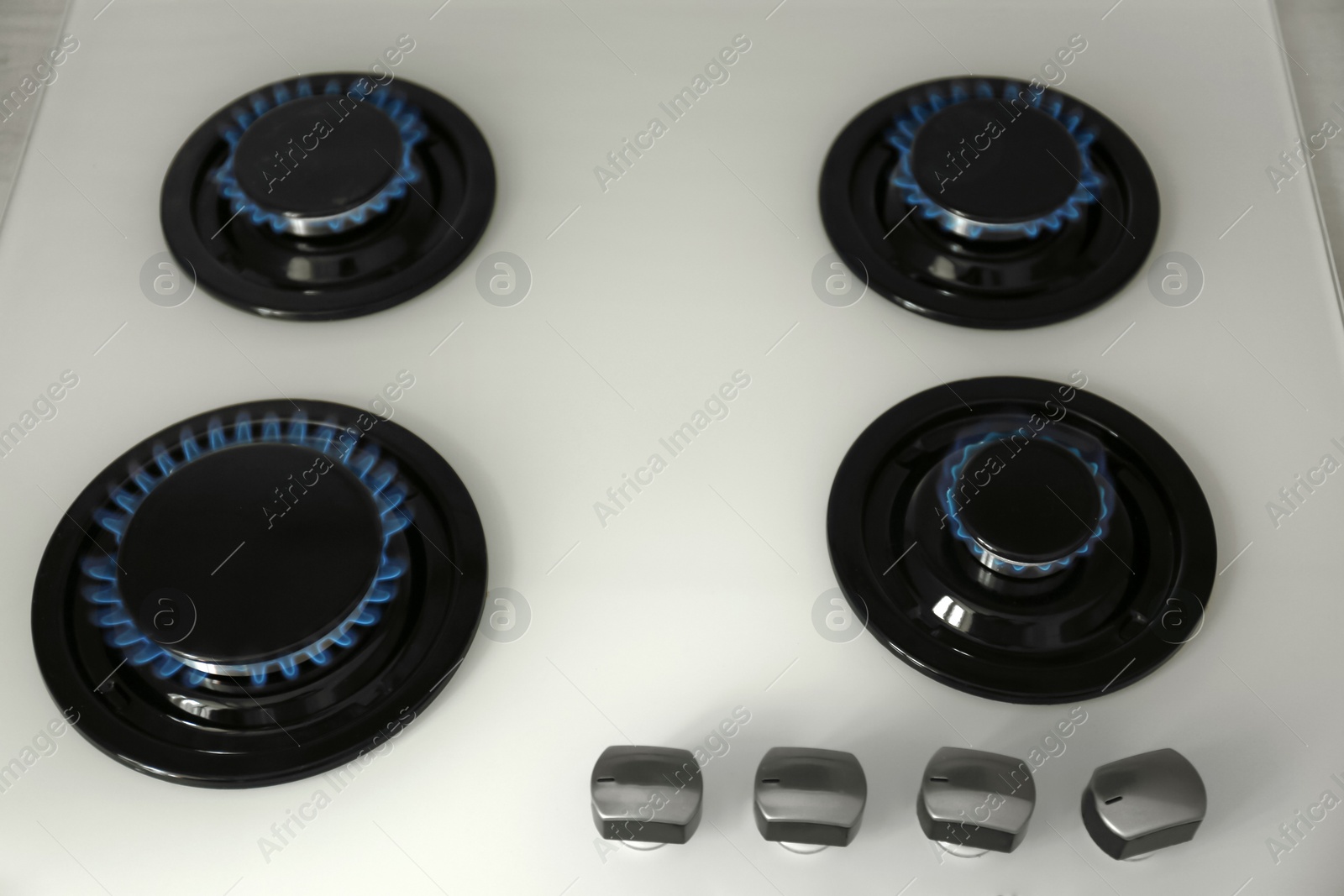 Photo of Gas burners with blue flame on modern stove