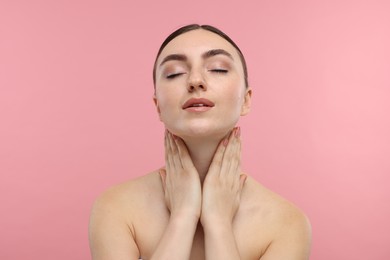 Photo of Beautiful woman touching her neck on pink background