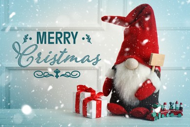 Image of Merry Christmas! Cute gnome, gift boxes and toy train on white wooden table 