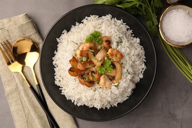 Photo of Delicious rice with parsley and mushrooms served on grey table, flat lay