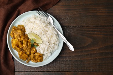 Photo of Delicious chicken curry with rice on wooden table, top view. Space for text