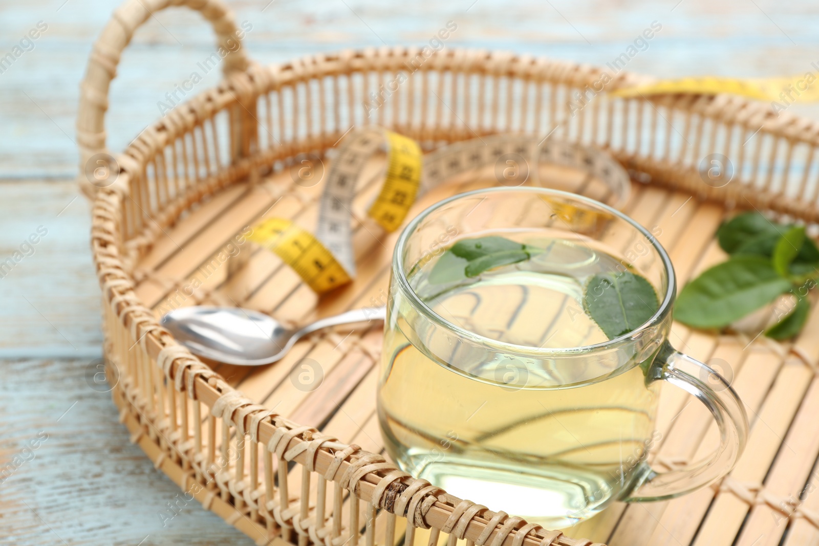 Photo of Diet herbal tea with green leaves on wooden table, closeup