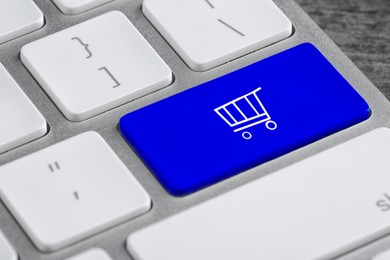 Online store. Blue button with shopping cart on computer keyboard, closeup