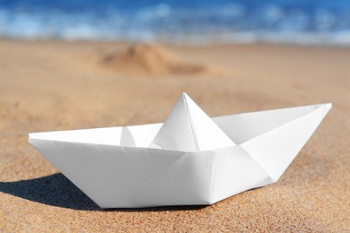 Photo of White paper boat near sea on sunny day, closeup