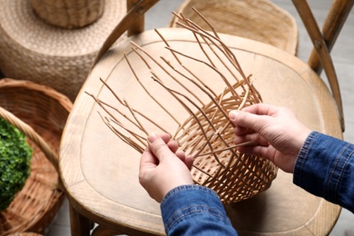 Woman weaving wicker basket indoors, closeup view