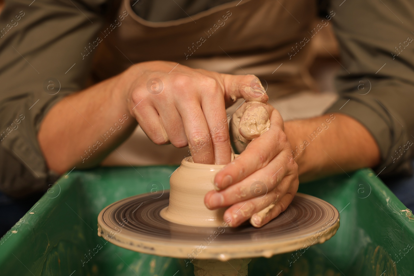 Photo of Clay crafting. Man making bowl on potter's wheel, closeup