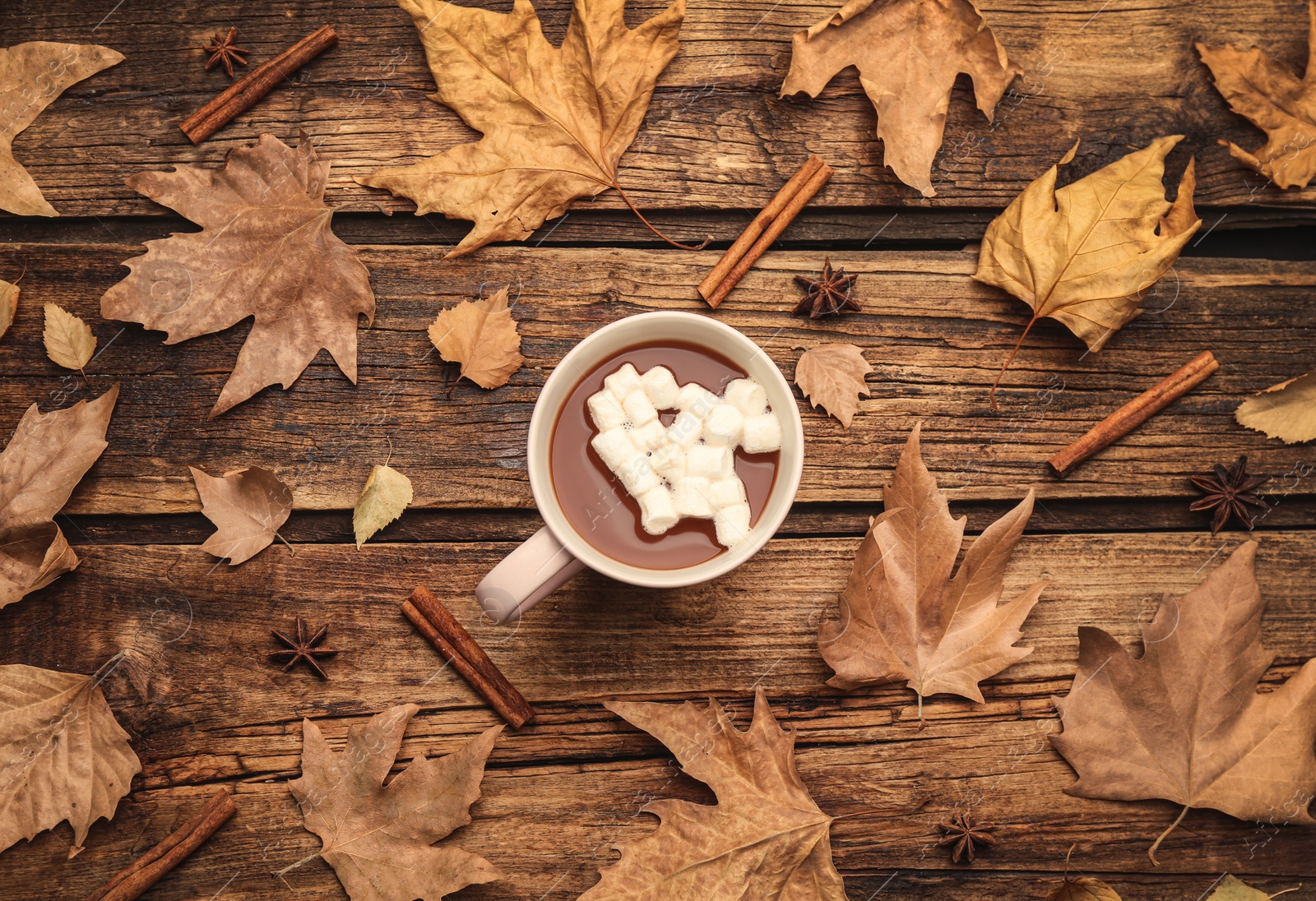 Photo of Flat lay composition with cup of hot drink and autumn leaves on wooden table. Cozy atmosphere