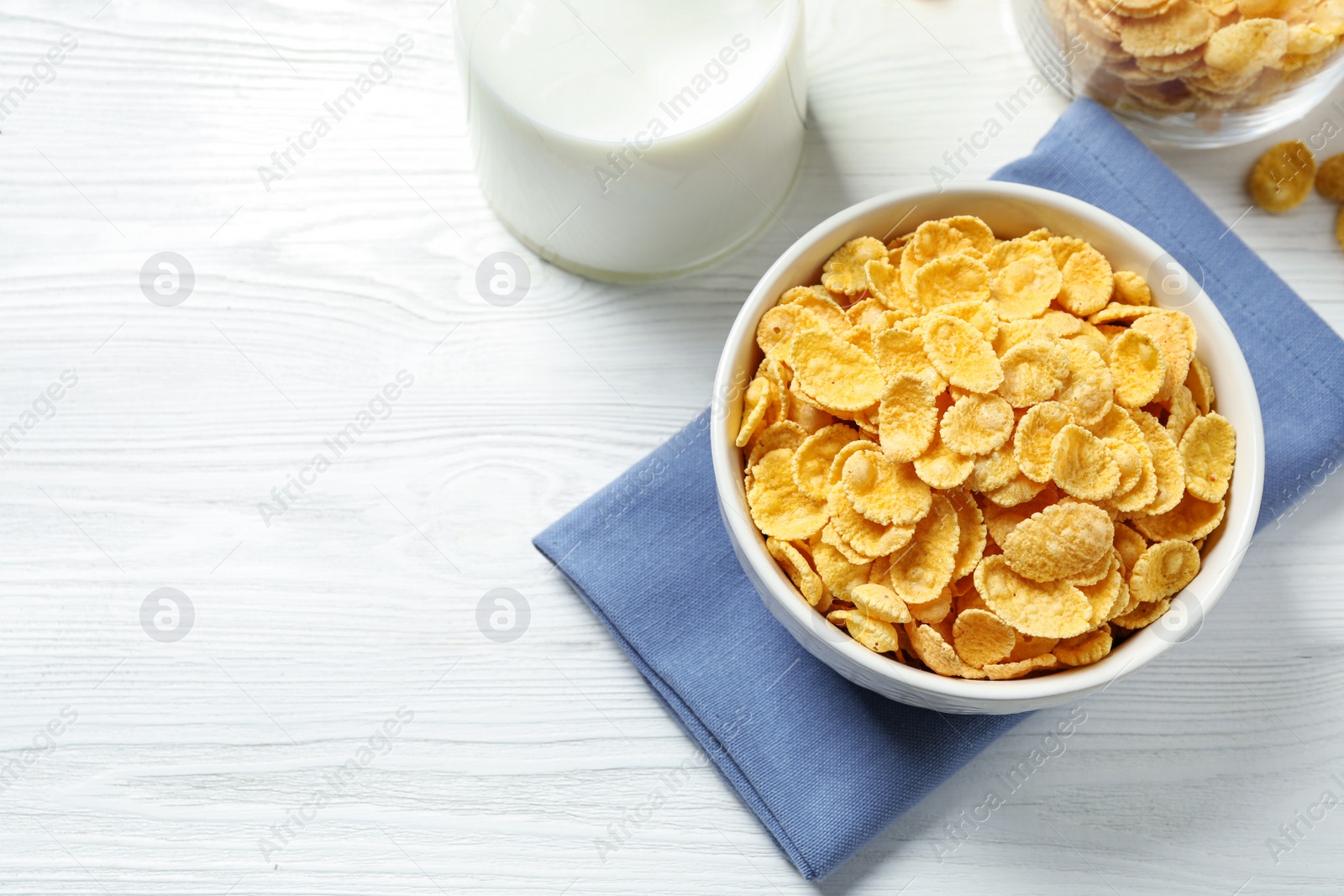 Photo of Tasty corn flakes on white wooden table, flat lay. Space for text