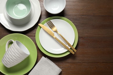 Photo of Beautiful ceramic dishware, cup and cutlery on wooden table, flat lay. Space for text