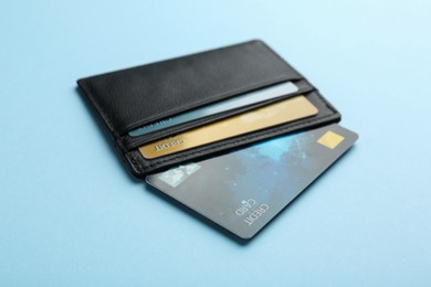 Photo of Leather card holder with credit cards on light blue background