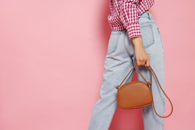 Woman in fashionable outfit with stylish bag on pink background, closeup. Space for text