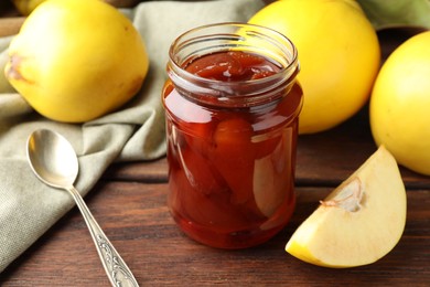 Photo of Tasty homemade quince jam in jar and fruits on wooden table