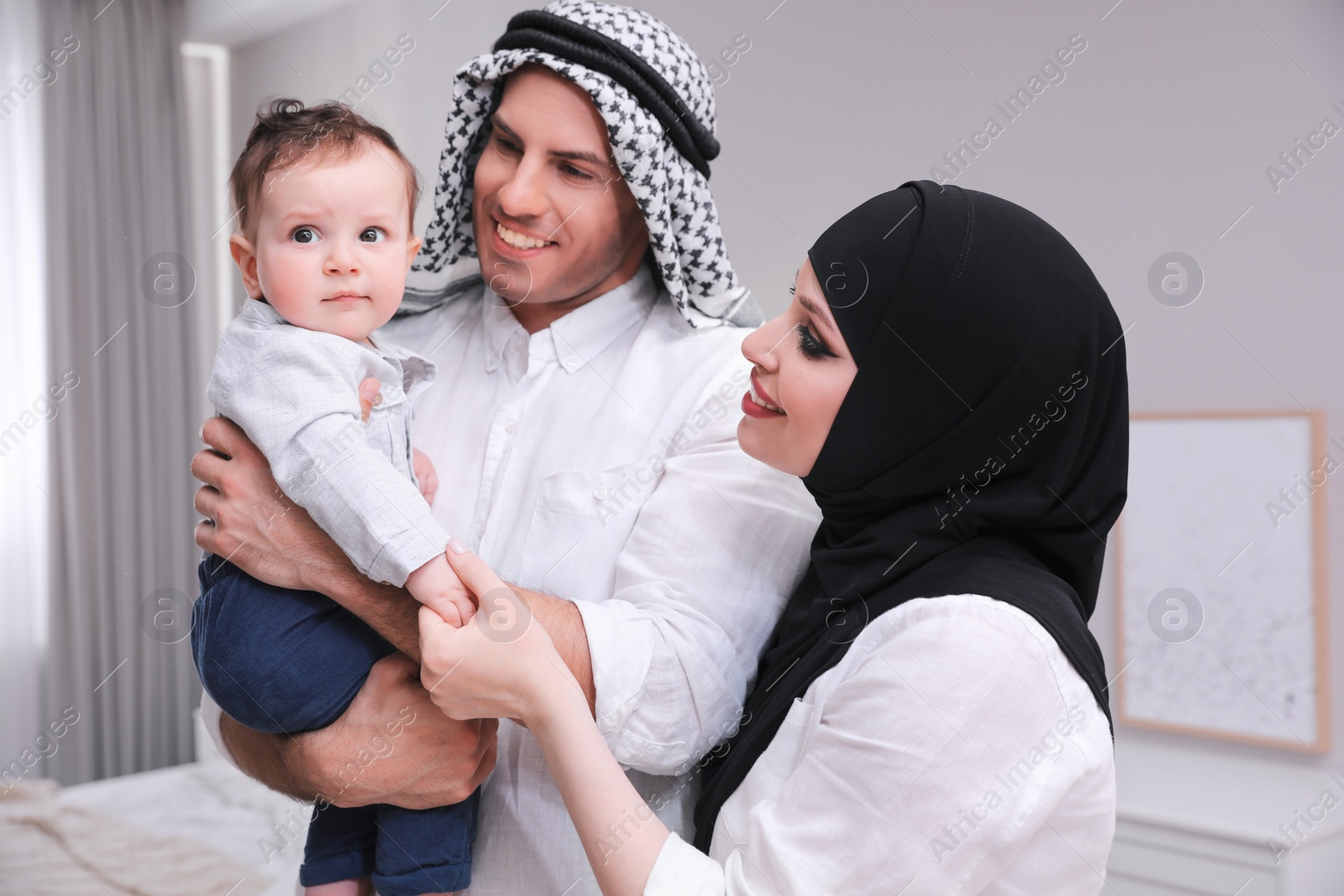 Photo of Happy Muslim family with little son in bedroom