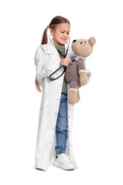 Little girl playing doctor with toy bear on white background