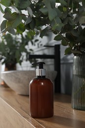 Photo of Soap bottle and eucalyptus branches near vessel sink on bathroom vanity. Interior design