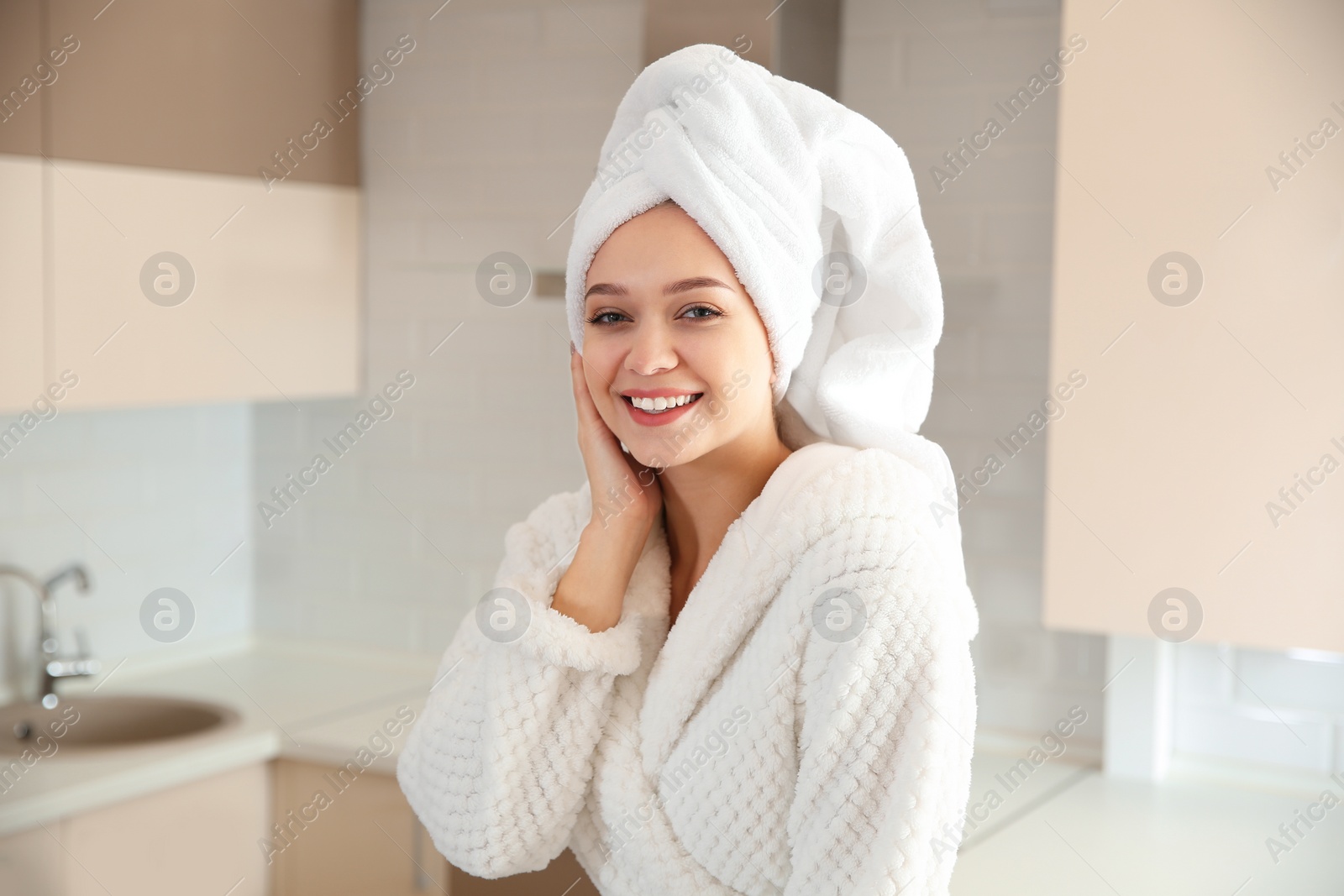 Photo of Beautiful woman with towel on head in kitchen at home