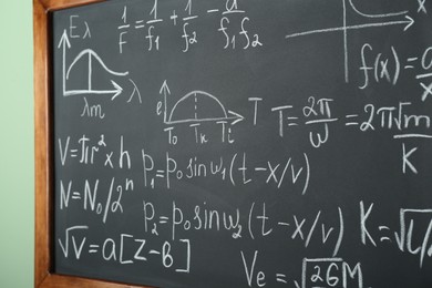 Photo of Chalkboard with many different math formulas on green wall, closeup