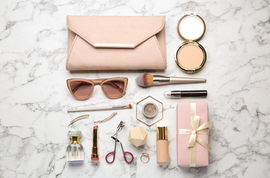 Flat lay composition with different luxury makeup products and accessories on white marble table