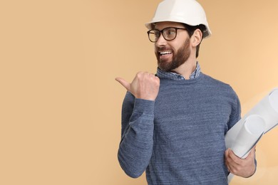 Photo of Architect in hard hat with drafts pointing at something on beige background, space for text