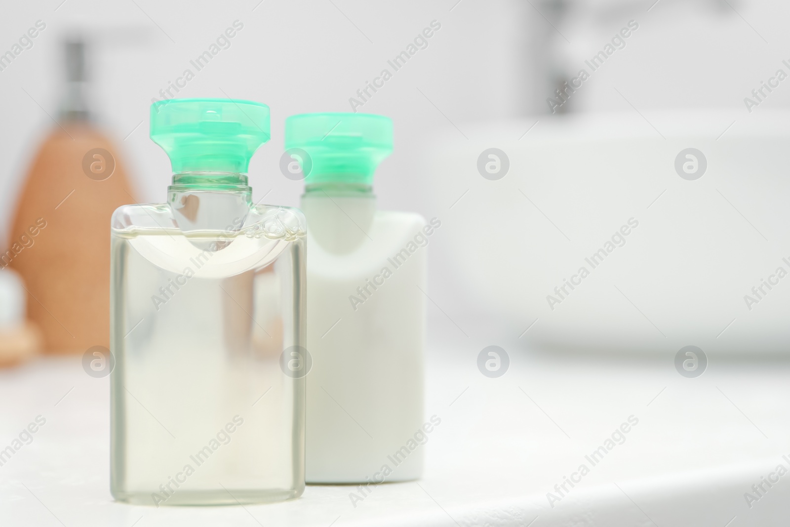 Photo of Mini bottles of cosmetic products on white table against blurred background. Space for text