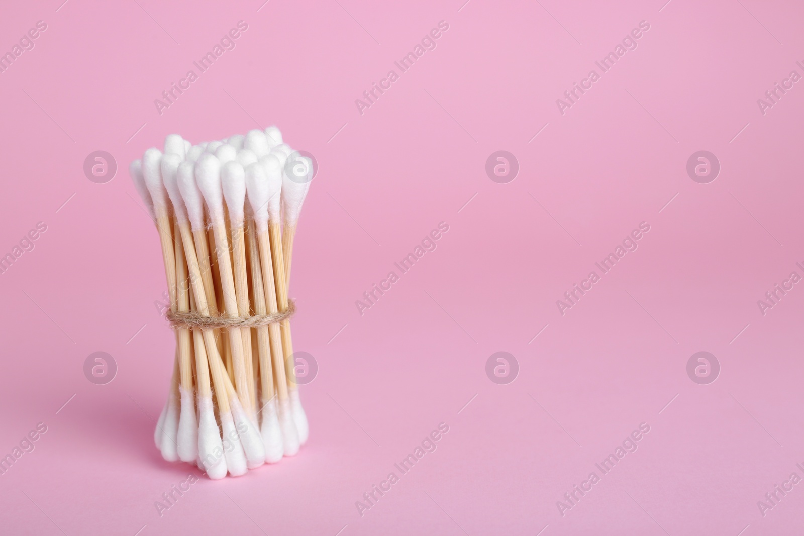 Photo of Bunch of wooden cotton buds on pink background. Space for text