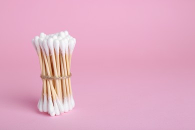 Bunch of wooden cotton buds on pink background. Space for text