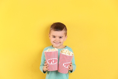 Photo of Cute little boy with popcorn on color background