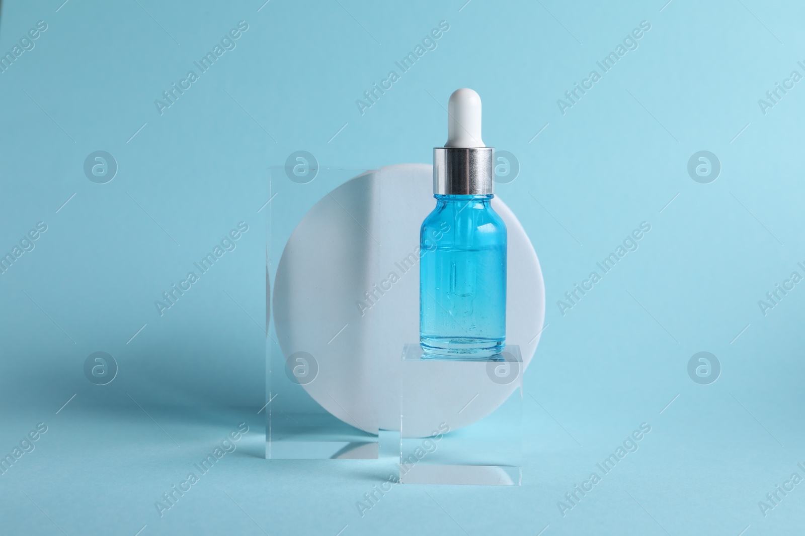 Photo of Stylish presentation of cosmetic serum on light blue background