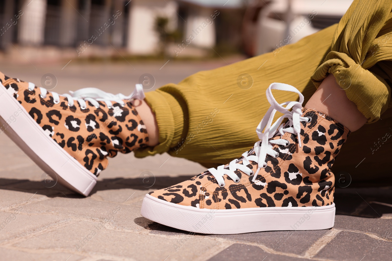 Photo of Woman wearing sneakers with leopard print outdoors, closeup