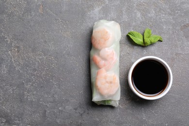 Photo of Tasty spring roll, mint and soy sauce on grey textured table, flat lay. Space for text