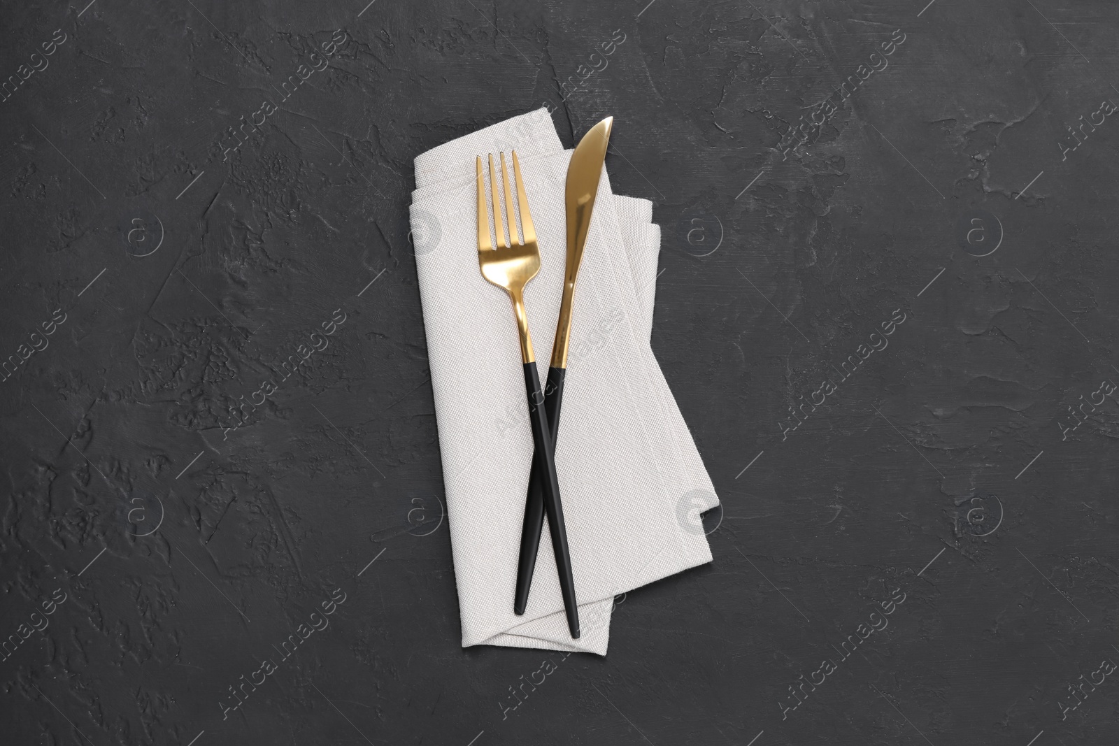 Photo of Beautiful cutlery set and kitchen towel on black table, top view