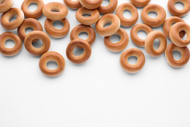 Photo of Many tasty dry bagels (sushki) on white background, flat lay. Space for text