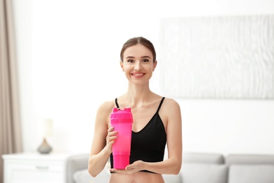 Photo of Athletic young woman with protein shake at home