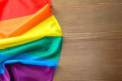 Photo of Rainbow gay flag on wooden background, top view with space for text. LGBT concept