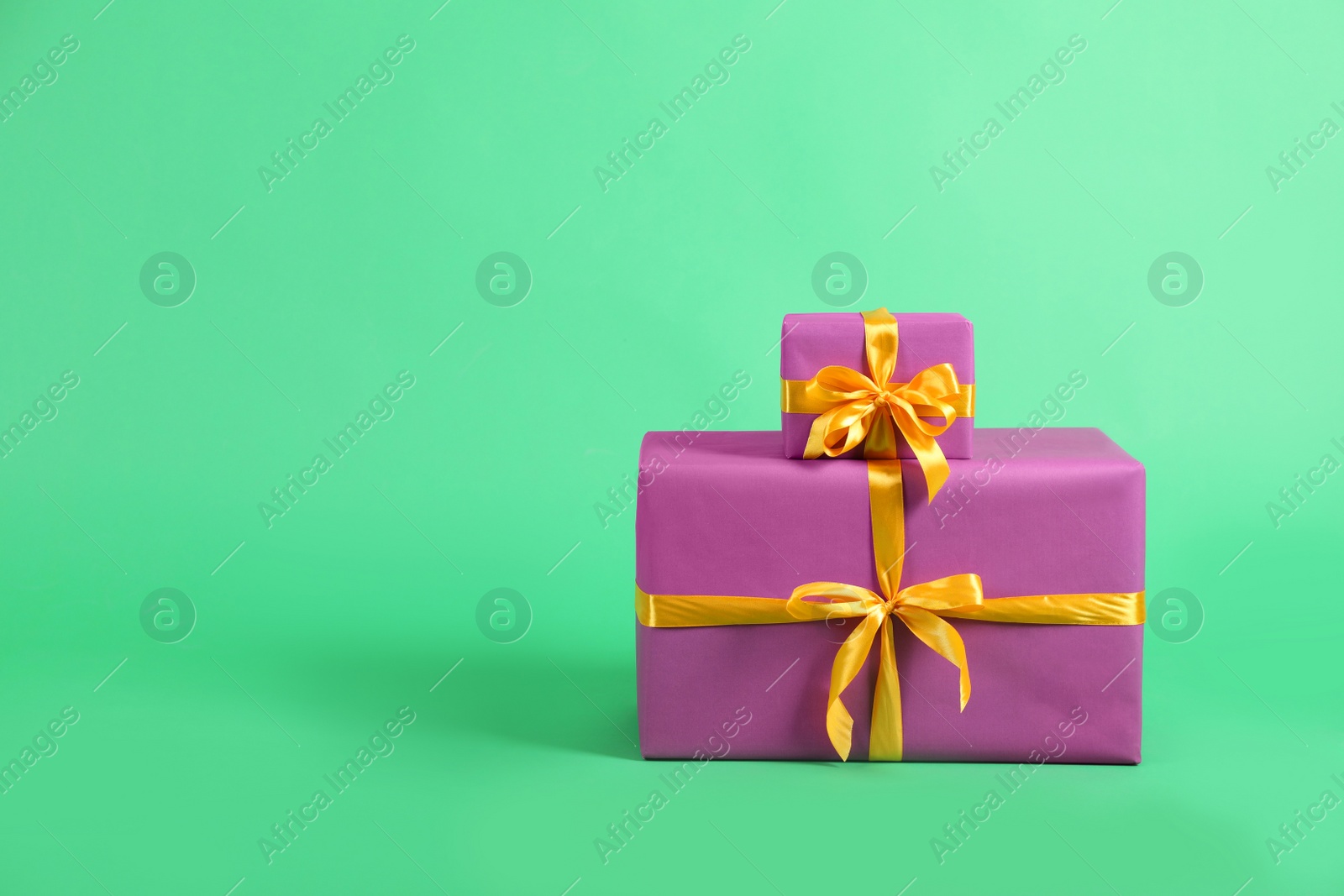 Photo of Beautifully wrapped gift boxes on green background. Space for text