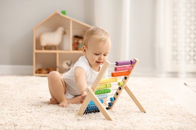 Photo of Children toys. Cute little boy playing with wooden abacus on rug at home