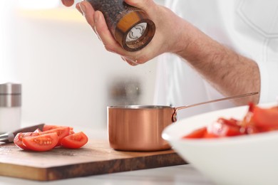 Photo of Professional chef adding pepper into scoop at table in kitchen, closeup