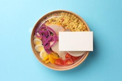 Photo of Tasty food in container on light blue background, top view. Space for text