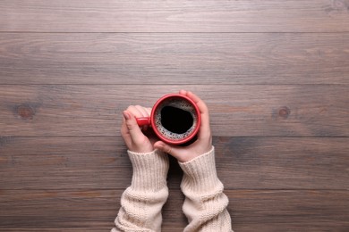 Photo of Woman with cup of coffee at wooden table, top view. Space for text