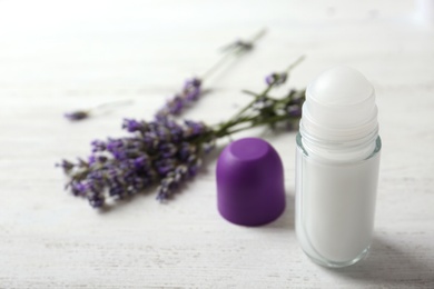 Photo of Female deodorant and lavender flowers on white wooden table. Space for text