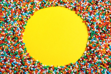 Photo of Frame of bright colorful sprinkles on yellow background, flat lay with space for text. Confectionery decor