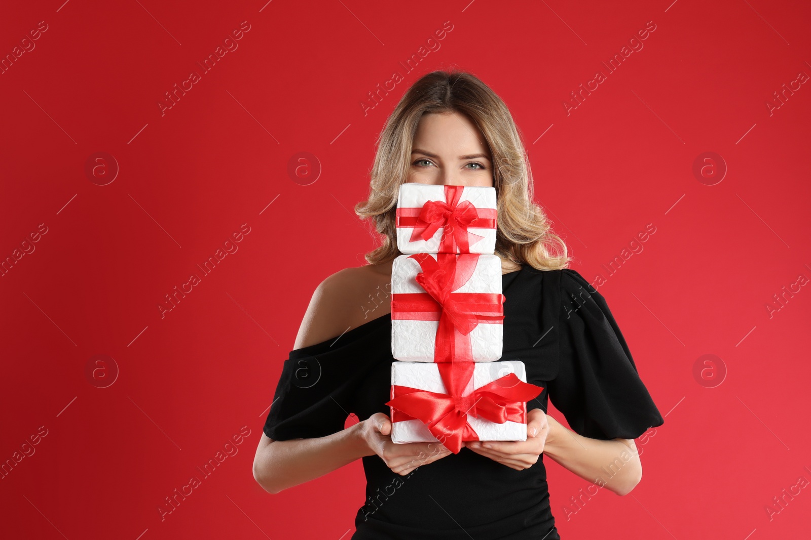 Photo of Beautiful young woman with Christmas presents on red background