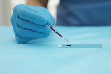 Photo of Doctor with blood sample from finger at table, closeup