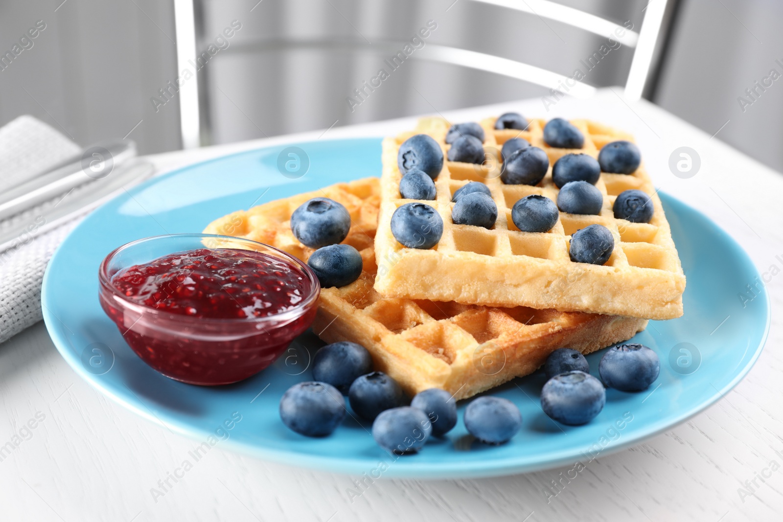 Photo of Delicious waffles with blueberries served on white table, closeup