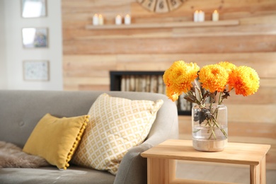 Beautiful flowers in vase on table in room, closeup. Cozy interior inspired by autumn colors